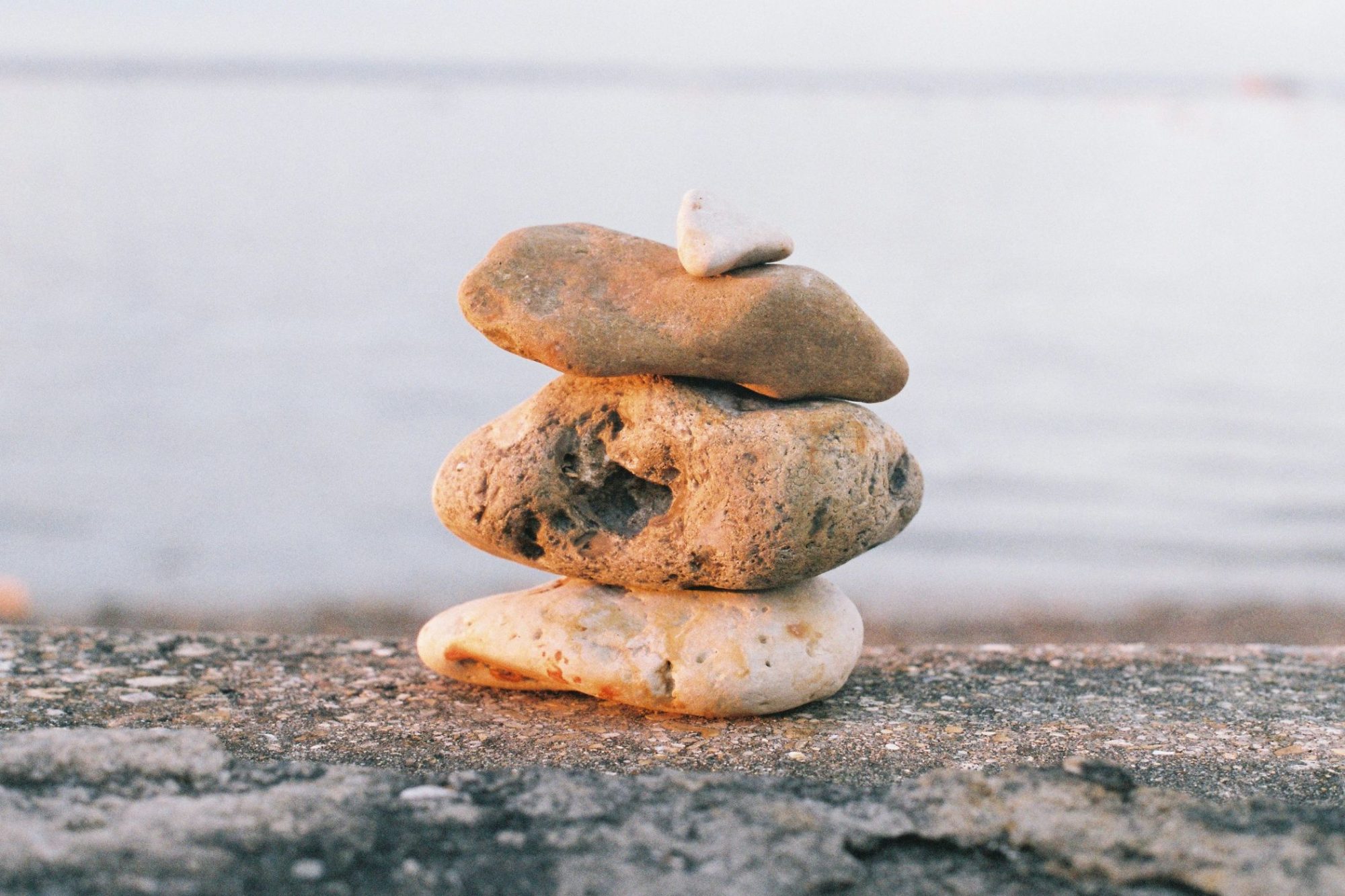 rocks stacked on the beach by the ocean - illustration for saas website structure